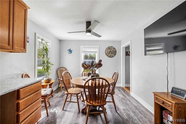 dining space featuring ceiling fan, baseboards, and dark wood-style floors