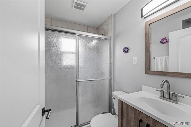 full bathroom featuring toilet, visible vents, vanity, and a shower with shower door