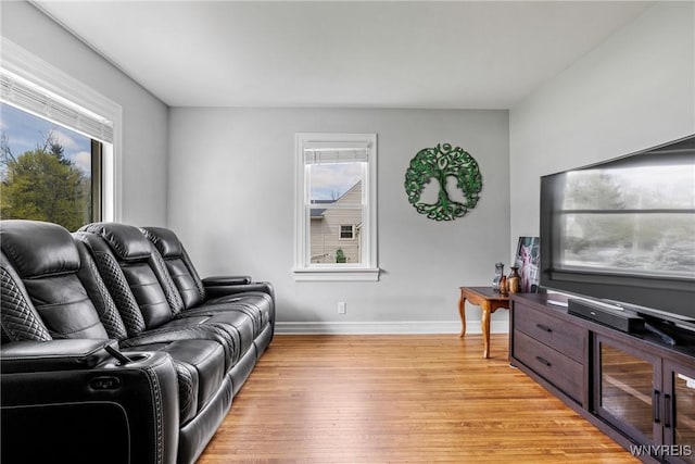 living area with baseboards, light wood-type flooring, and plenty of natural light