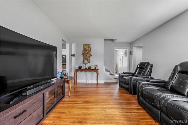 living area with baseboards, stairway, and light wood finished floors