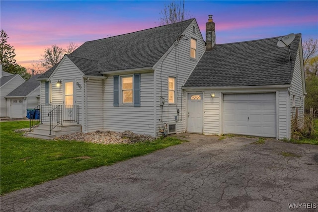 new england style home with an attached garage, a chimney, aphalt driveway, a front yard, and roof with shingles