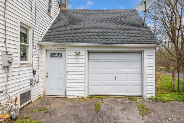 garage featuring driveway and fence