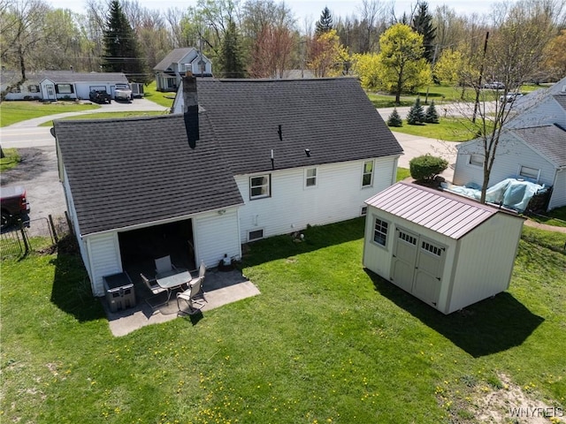 rear view of house featuring an outdoor structure, a standing seam roof, fence, and a lawn