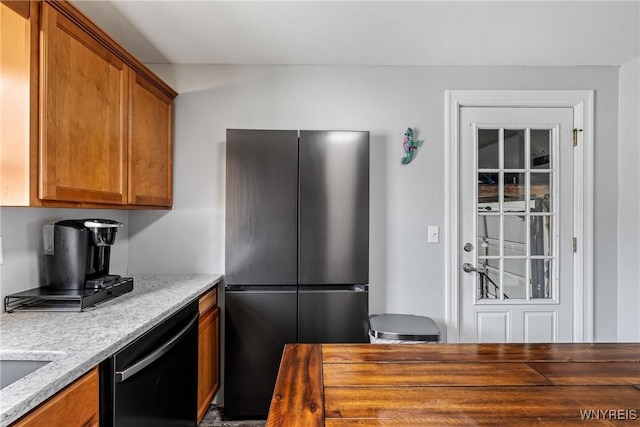 kitchen featuring freestanding refrigerator, brown cabinets, and dishwasher