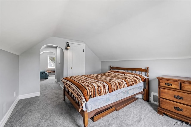 carpeted bedroom featuring vaulted ceiling, visible vents, baseboards, and arched walkways