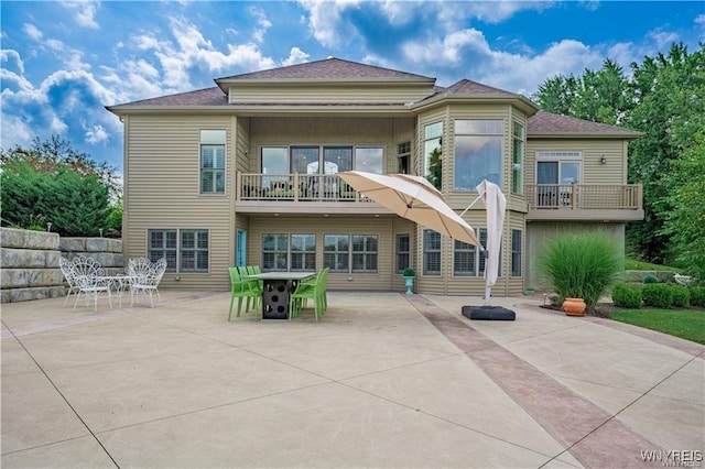 back of house with a balcony, a patio area, and outdoor dining area