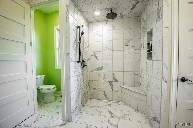 bathroom featuring toilet, marble finish floor, and a tile shower