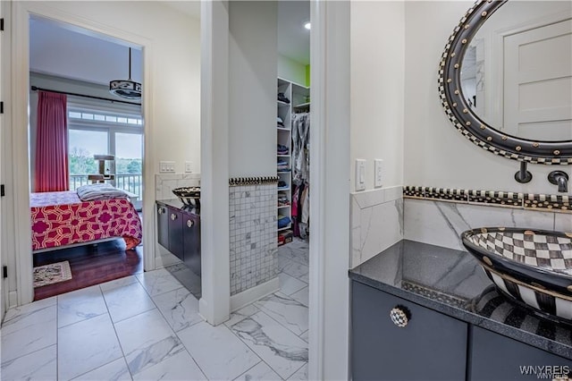 bathroom featuring tile walls, marble finish floor, a wainscoted wall, and a walk in closet