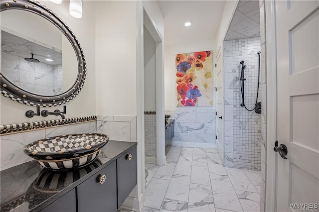 bathroom featuring a tile shower, tile walls, wainscoting, marble finish floor, and recessed lighting