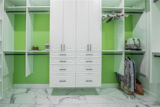 walk in closet featuring marble finish floor