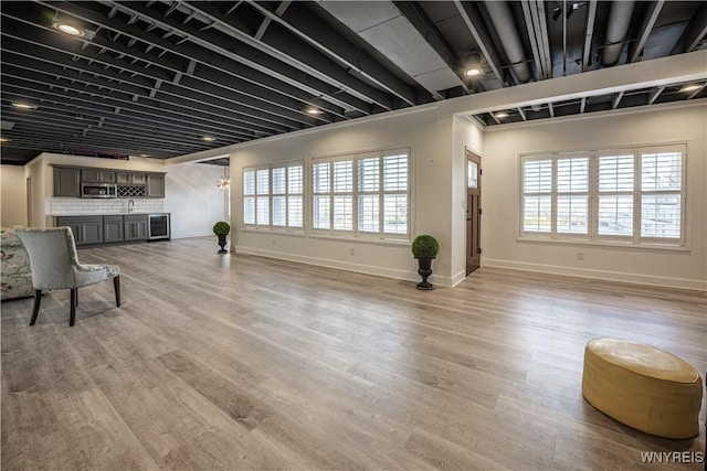 interior space with light wood finished floors, baseboards, plenty of natural light, and wet bar