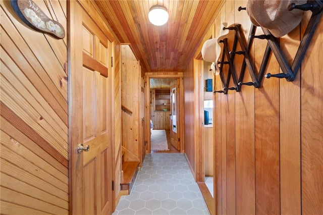 hall with wooden walls, tile patterned floors, and wood ceiling