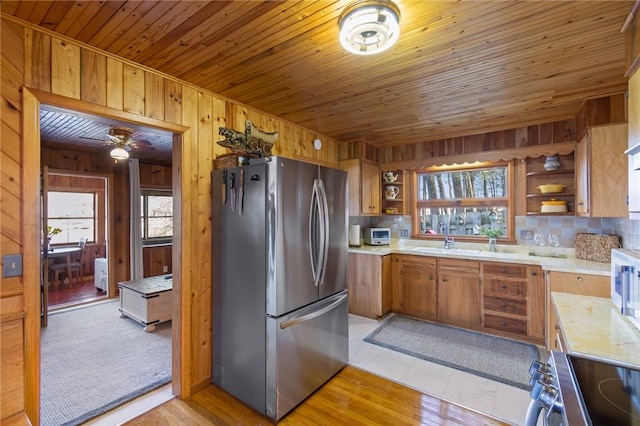 kitchen featuring open shelves, light countertops, stainless steel appliances, and wooden walls