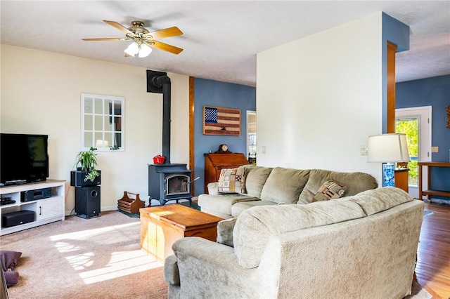 living room with a wood stove and a ceiling fan