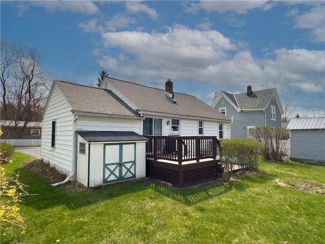 back of property featuring a storage unit, a wooden deck, a yard, and an outbuilding