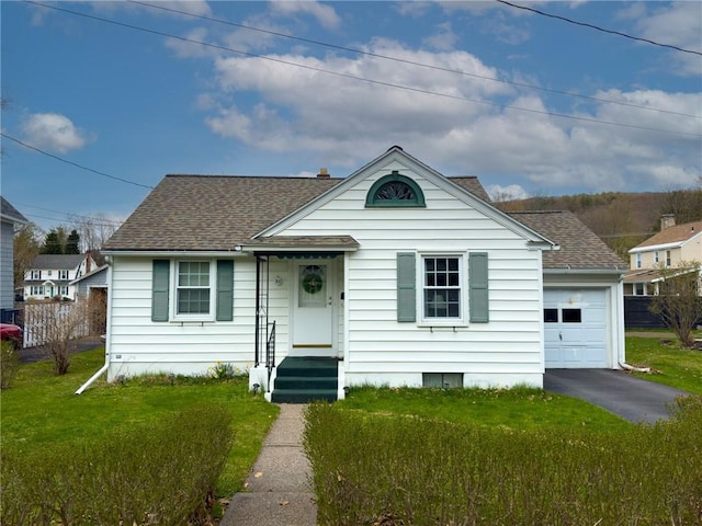 bungalow-style house featuring a front yard, roof with shingles, driveway, and a detached garage