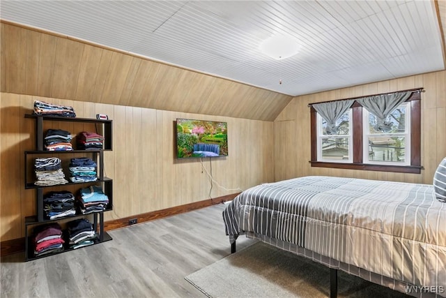 bedroom with vaulted ceiling, wooden walls, wood ceiling, and wood finished floors