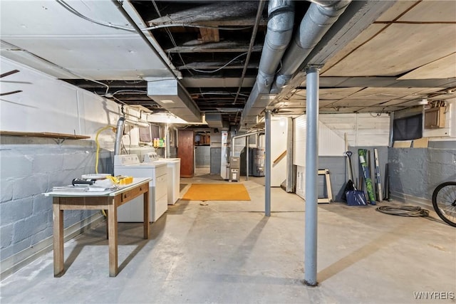 unfinished below grade area featuring heating unit, water heater, and washer and clothes dryer