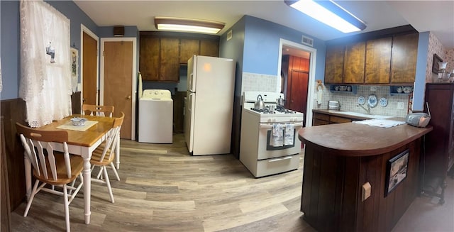 kitchen with visible vents, white appliances, washer / dryer, light wood-style floors, and tasteful backsplash