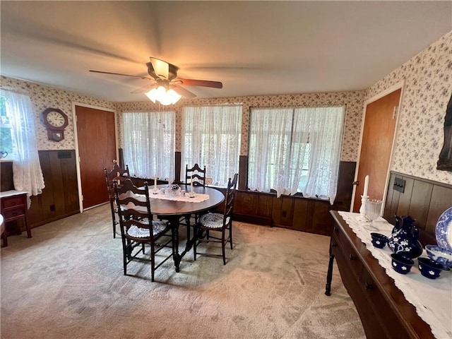 dining area featuring a ceiling fan, a wealth of natural light, wainscoting, and wallpapered walls