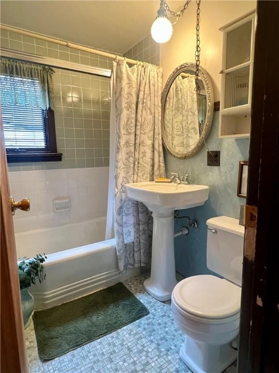 bathroom with toilet, shower / tub combo, and a sink