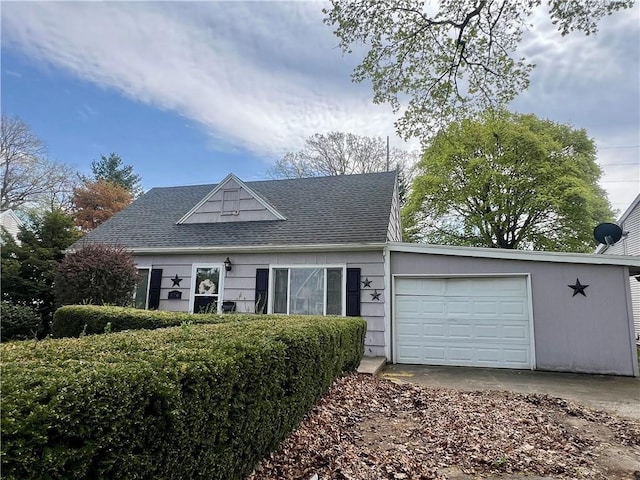 cape cod home with concrete driveway, an attached garage, and a shingled roof
