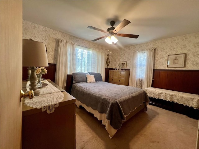bedroom with a ceiling fan, carpet flooring, a wainscoted wall, and wallpapered walls