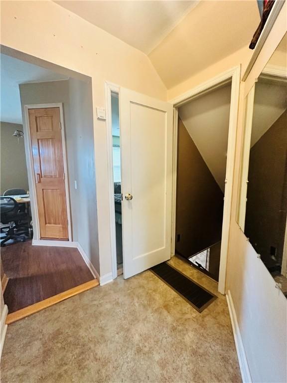 foyer entrance with lofted ceiling, baseboards, and carpet