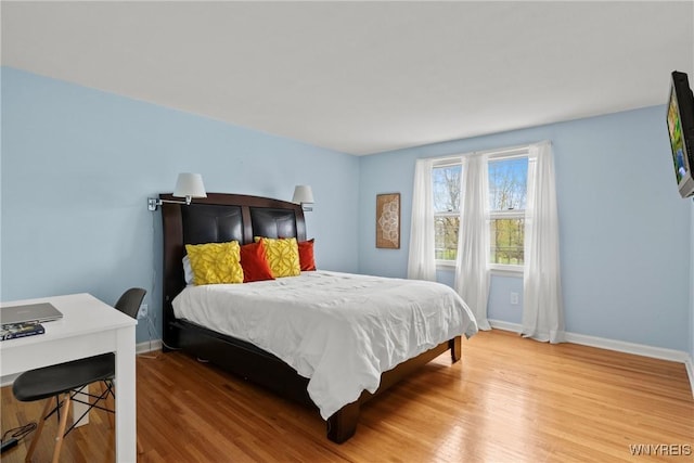 bedroom featuring wood finished floors, baseboards, and an office area