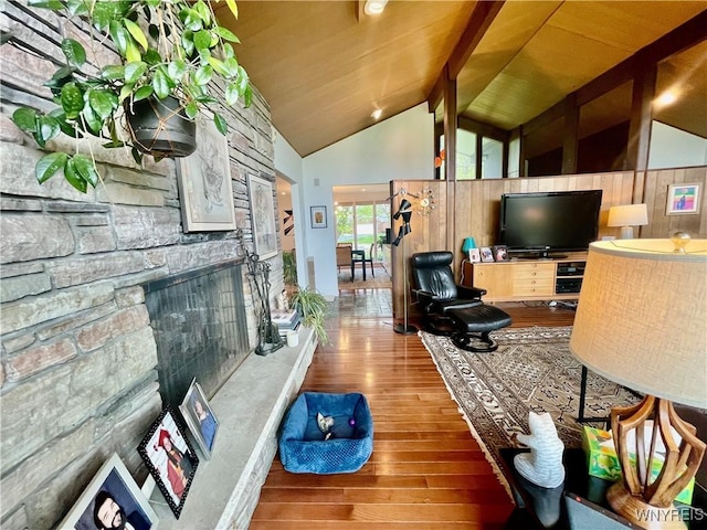 living area featuring a fireplace, beam ceiling, high vaulted ceiling, and wood finished floors