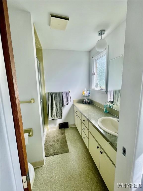 bathroom with a stall shower, vanity, and baseboards