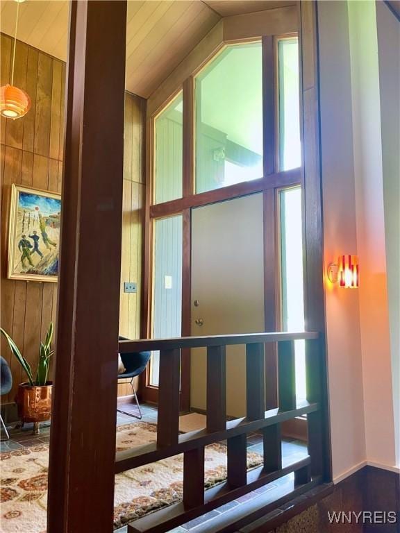 entryway featuring vaulted ceiling, wooden walls, and a wealth of natural light