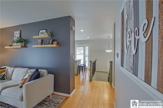 corridor featuring an upstairs landing, light wood-style flooring, baseboards, and recessed lighting