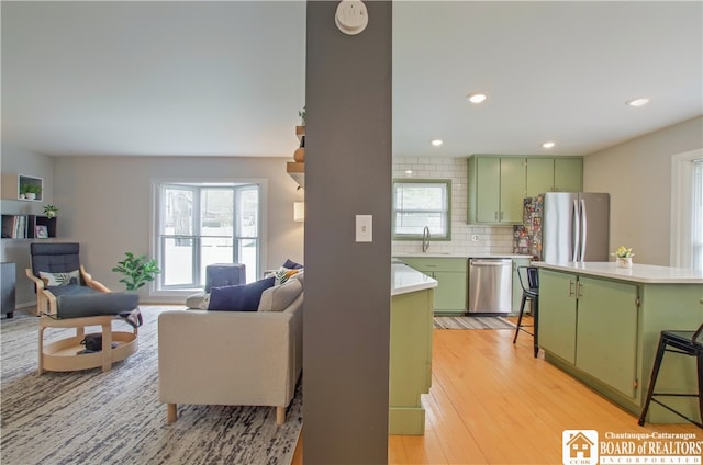 kitchen featuring a sink, light countertops, plenty of natural light, green cabinets, and appliances with stainless steel finishes