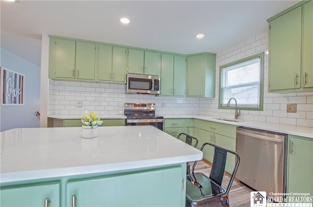 kitchen with a sink, stainless steel appliances, light countertops, and green cabinetry