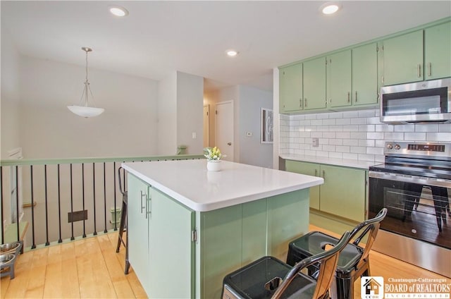 kitchen featuring stainless steel appliances, green cabinets, light wood finished floors, light countertops, and tasteful backsplash