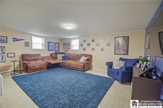 living room with light floors, wooden walls, baseboards, and ornamental molding