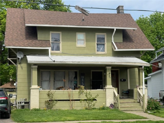 view of front of home with covered porch, roof with shingles, a chimney, and a front lawn