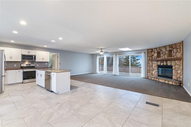 7893 Lake Rd, Sodus, NY 14555 - kitchen featuring a sink, stainless steel appliances, open floor plan, a stone fireplace, and recessed lighting