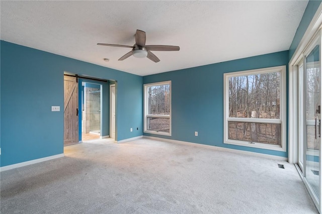 7893 Lake Rd, Sodus, NY 14555 - unfurnished room featuring ceiling fan, a barn door, baseboards, and carpet floors