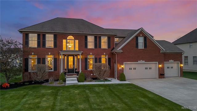 colonial house with concrete driveway, brick siding, a yard, and an attached garage