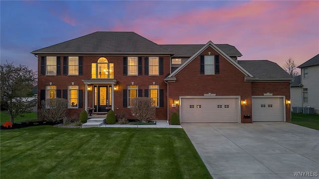 colonial inspired home with concrete driveway, brick siding, a yard, and an attached garage