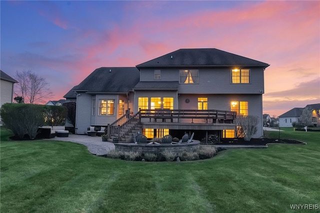 back of property at dusk with a yard, a wooden deck, and a patio