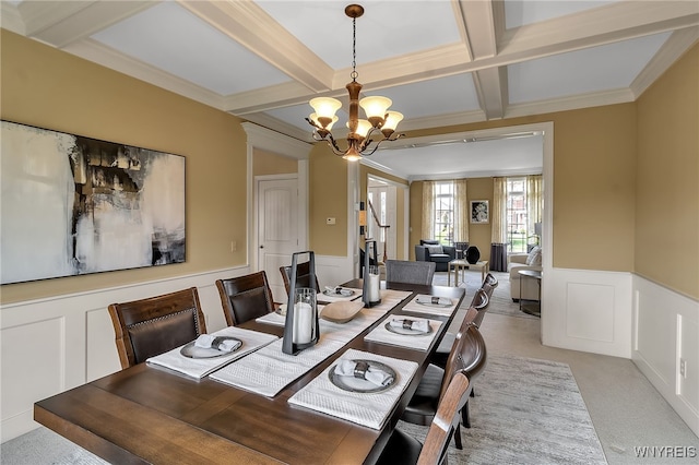 dining room featuring coffered ceiling, an inviting chandelier, wainscoting, a decorative wall, and light colored carpet