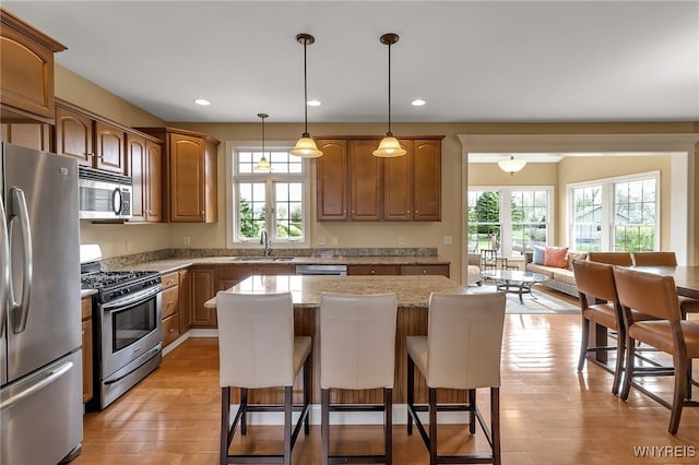 kitchen featuring light wood-style flooring, appliances with stainless steel finishes, a center island, and a kitchen bar