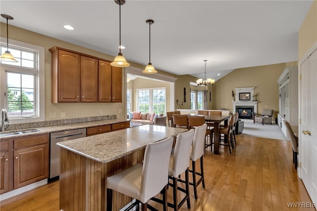 kitchen featuring a sink, dishwasher, a chandelier, open floor plan, and a stone fireplace