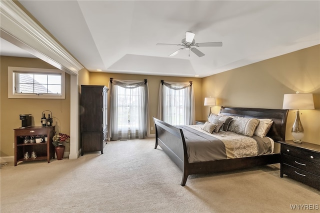 bedroom with a tray ceiling, multiple windows, baseboards, and light colored carpet