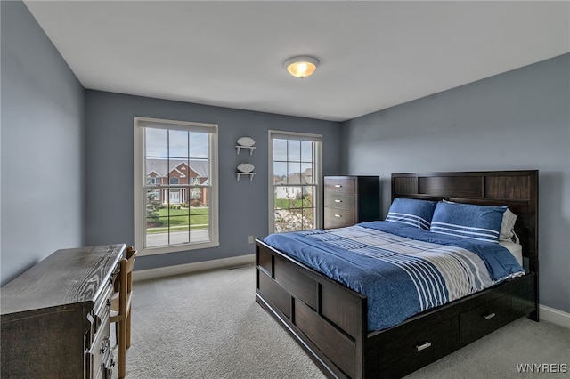 bedroom with light colored carpet and baseboards