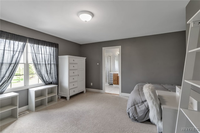 bedroom featuring baseboards, ensuite bath, visible vents, and light colored carpet