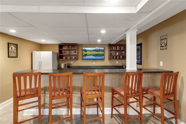 bar with indoor wet bar, freestanding refrigerator, a paneled ceiling, baseboards, and recessed lighting
